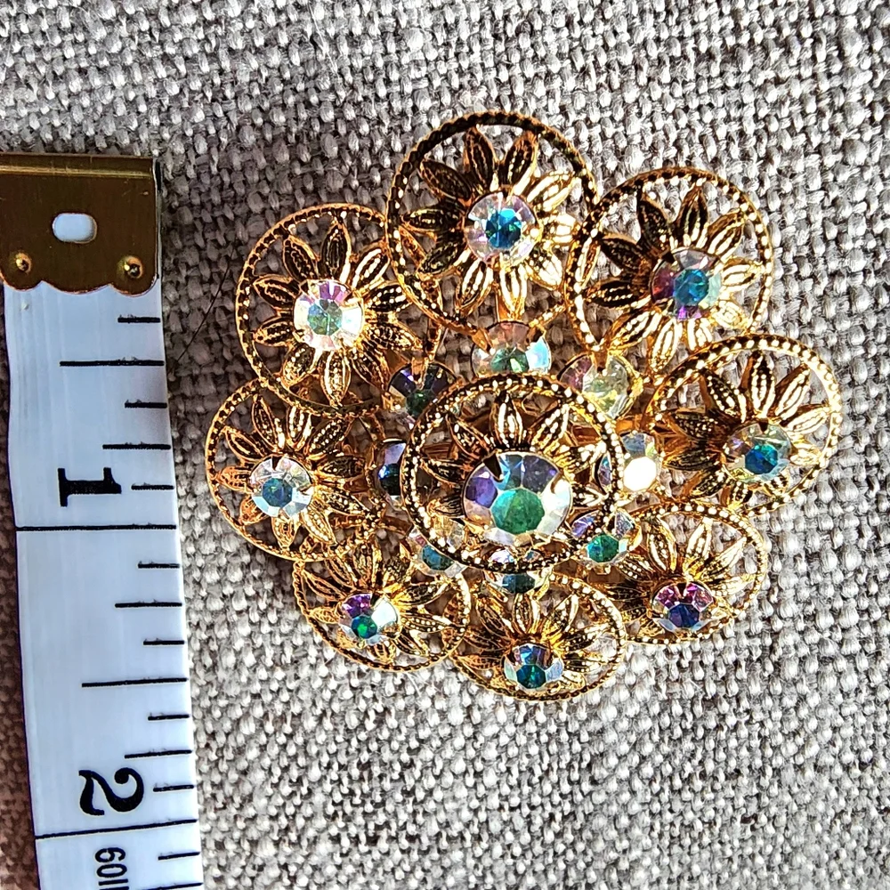 Vintage aurora borealis rhinestone gold-tone filigree floral brooch. 1960's